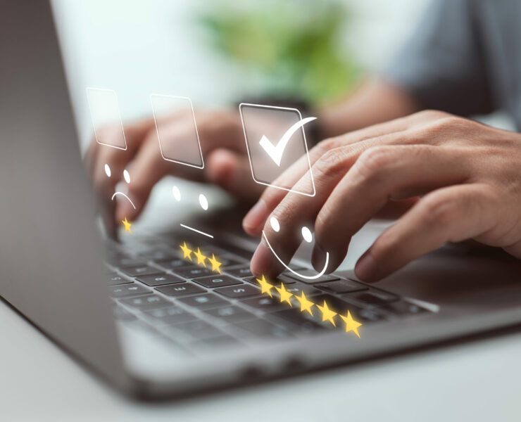 On the laptop keyboard, a businessman presses the face emoji. Concept for evaluating customer service.